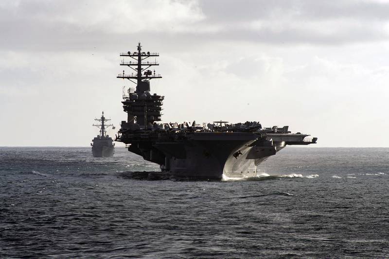 The aircraft carrier USS Nimitz (CVN 68) and Arleigh Burke-class guided-missile destroyer USS Ralph Johnson (DDG 114) steam in formation during a composite training unit exercise as part of the Nimitz Carrier Strike Group (CSG) on May 14, 2020, in the Pacific Ocean.