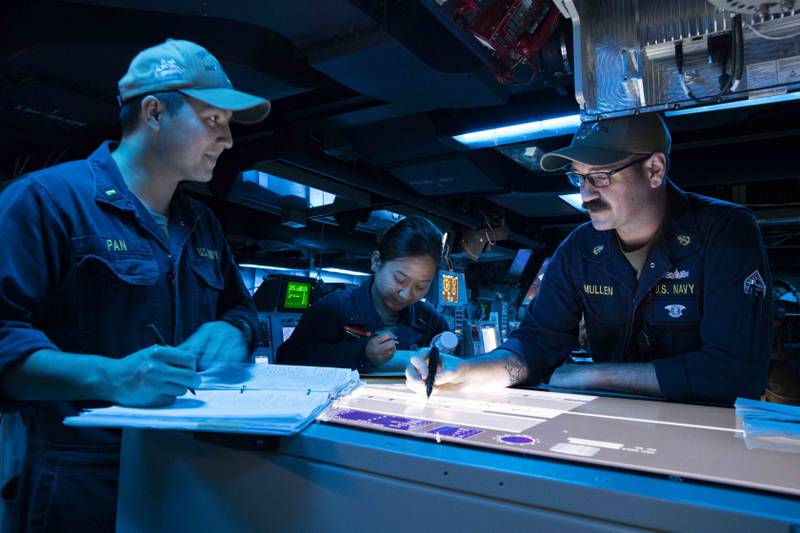 U.S. Navy Chief Sonar Technician (Surface) Andrew Mullen, right, provides instruction in the combat information center aboard the Arleigh Burke-class guided-missile destroyer USS Decatur.