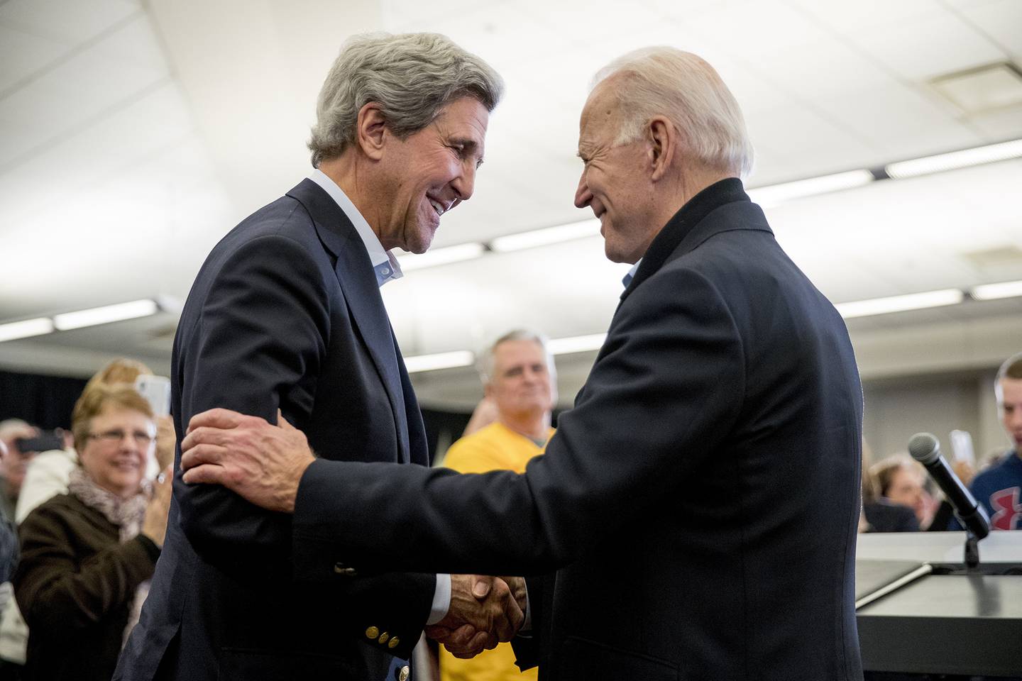 In this Feb. 1, 2020, file photo Democratic presidential candidate former Vice President Joe Biden smiles as former Secretary of State John Kerry, left, takes the podium to speak at a campaign stop at the South Slope Community Center in North Liberty, Iowa.