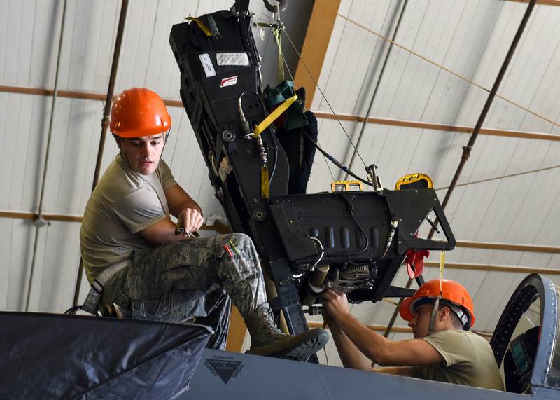 Senior Airman Blake Anguiano (left) and Airman 1st Class Jonathan Lamb, 4th Component Maintenance Squadron aircrew egress systems journeymen, install an ejection seat into an F-15E Strike Eagle at Seymour Johnson Air Force Base, North Carolina, Sept. 22, 2020.