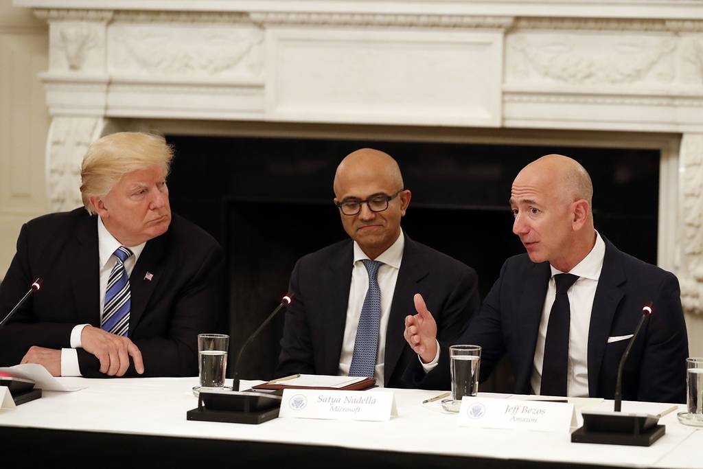 In this June 19, 2017, file photo President Donald Trump, left, and Satya Nadella, chief executive officer of Microsoft, center, listen as Jeff Bezos, chief executive officer of Amazon, speaks during an American Technology Council roundtable in the State Dinning Room of the White House in Washington.