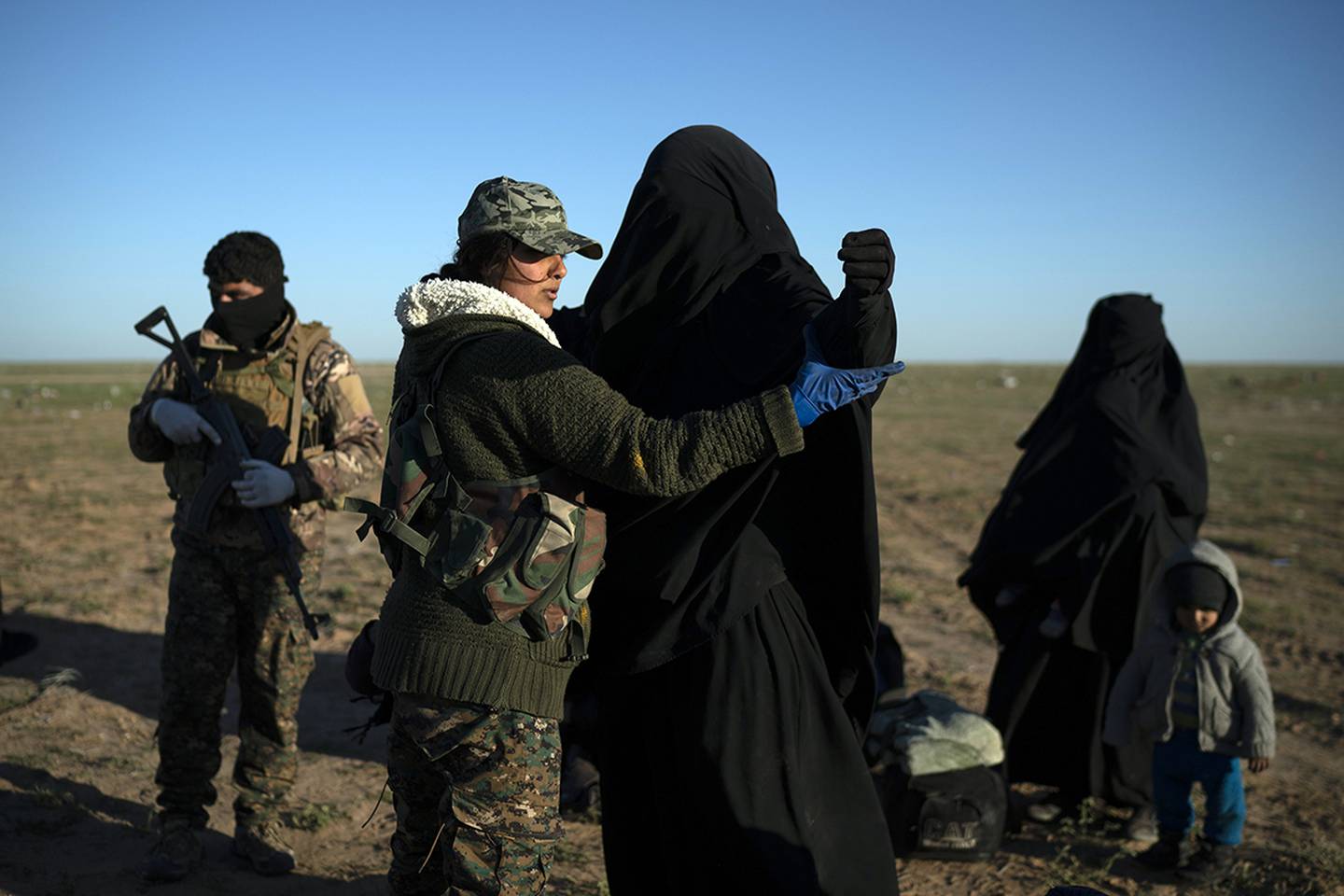 a woman is frisked by a U.S.-backed Syrian Democratic Forces fighter at a screening area after being evacuated out of the last territory held by Islamic State group militants.