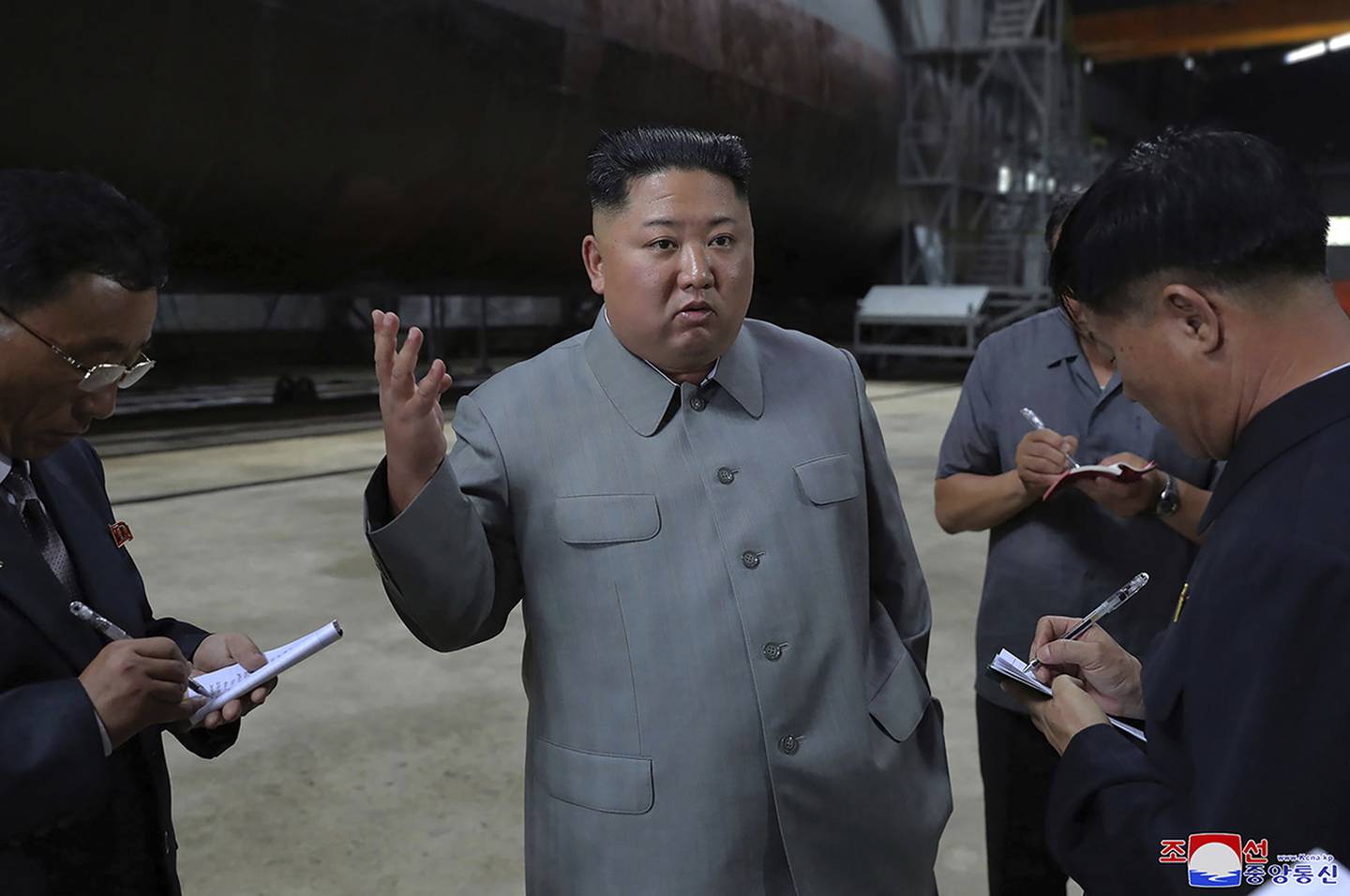 In this undated photo provided on Tuesday, July 23, 2019, North Korean leader Kim Jong Un, center, speaks while inspecting a newly built submarine to be deployed soon, at an unknown location in North Korea.