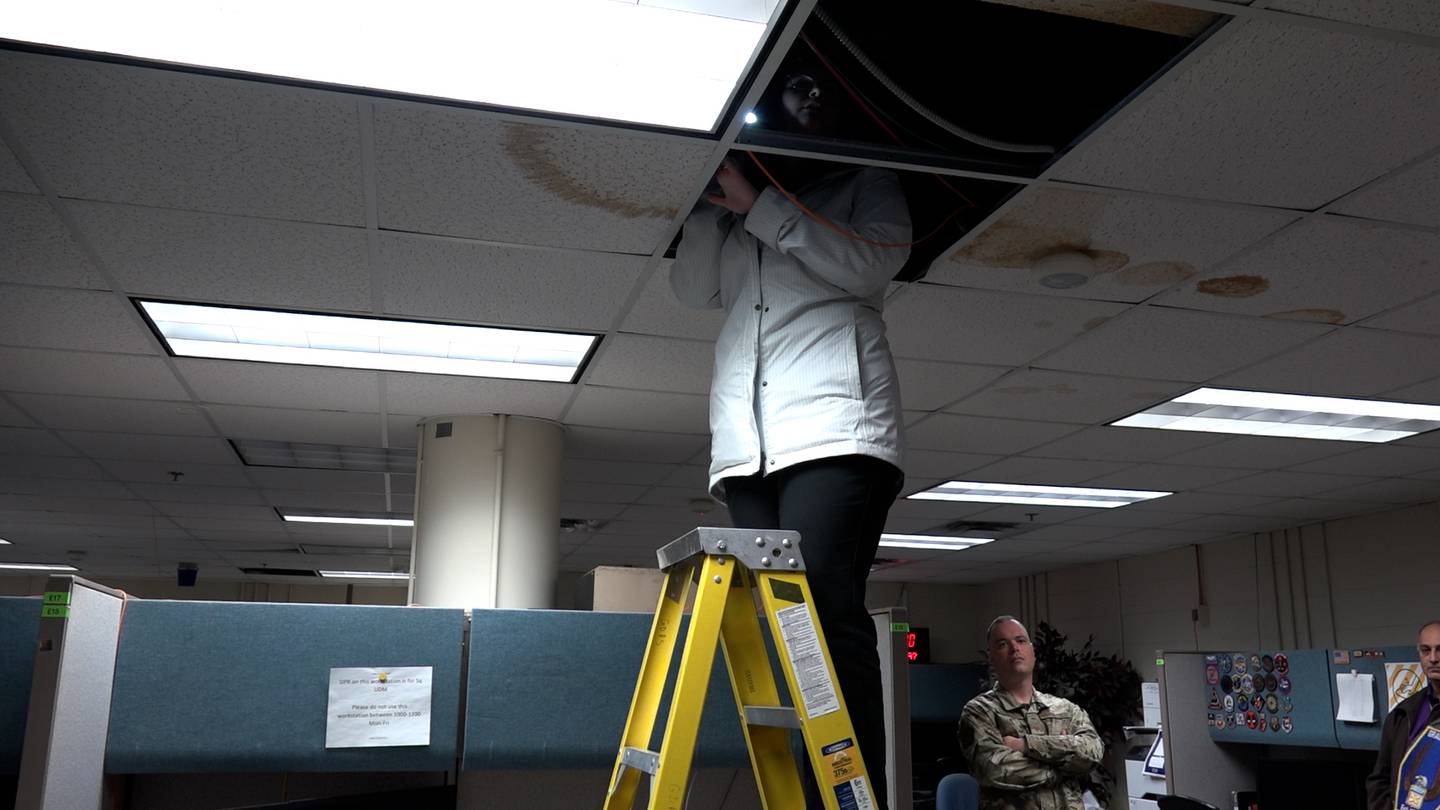 Air Force Times reporter Rachel Cohen peeks at damage to the inside of a ceiling at Offutt Air Force Base, Nebraska on April 25, 2022, where vehicles above are causing the concrete to deteriorate. (Daniel Woolfolk/Staff)