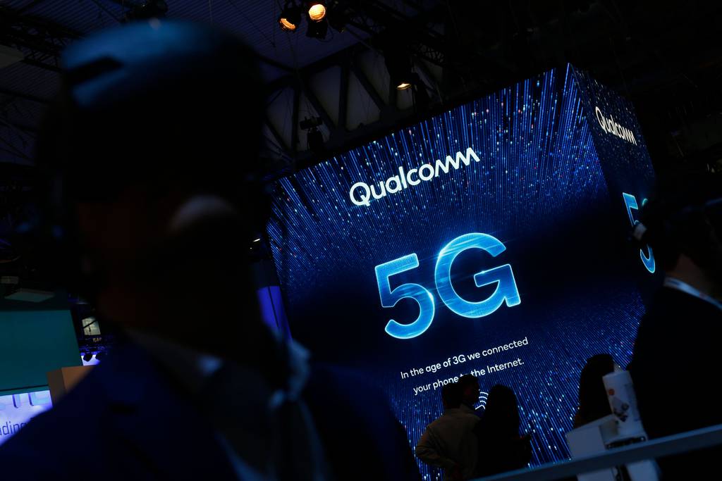 People walk past the Qualcomm stand at the Mobile World Congress event in February 2019.