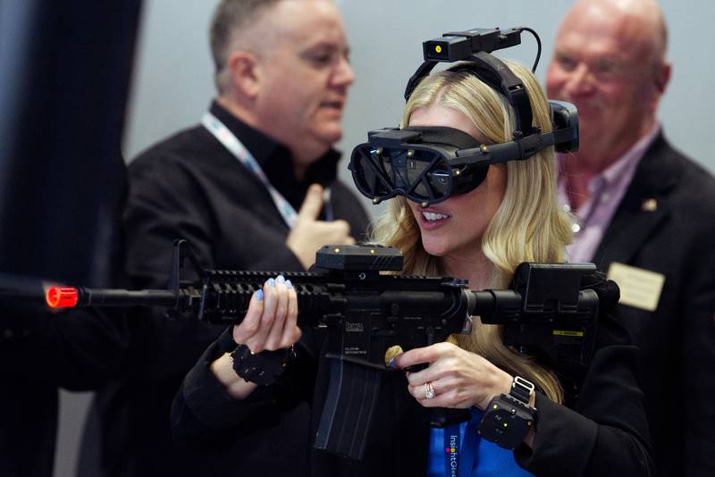 A woman engages with a shooting simulation at the General Dynamics Information Technology booth at the West 2024 conference in San Diego.